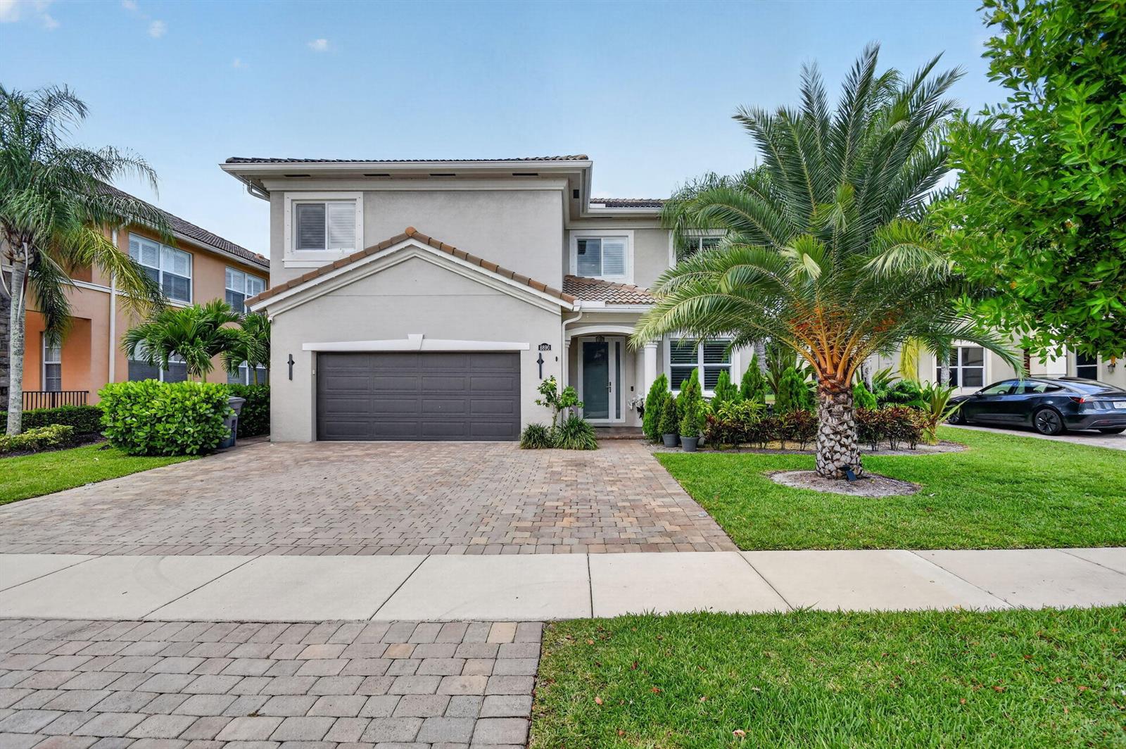 A two-story suburban house with a paved driveway, a garage, and a large palm tree — 8890 Cobblestone Point Circle, Boynton Beach FL 33472, BOYNTON BEACH, FL