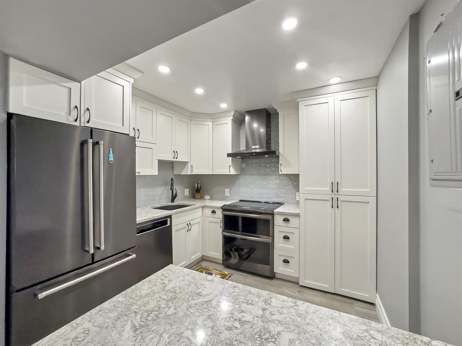 A kitchen features white cabinetry, stainless steel appliances, and a marble-patterned countertop — 2000 S Ocean Boulevard, Pompano Beach FL 33062, POMPANO BEACH, FL