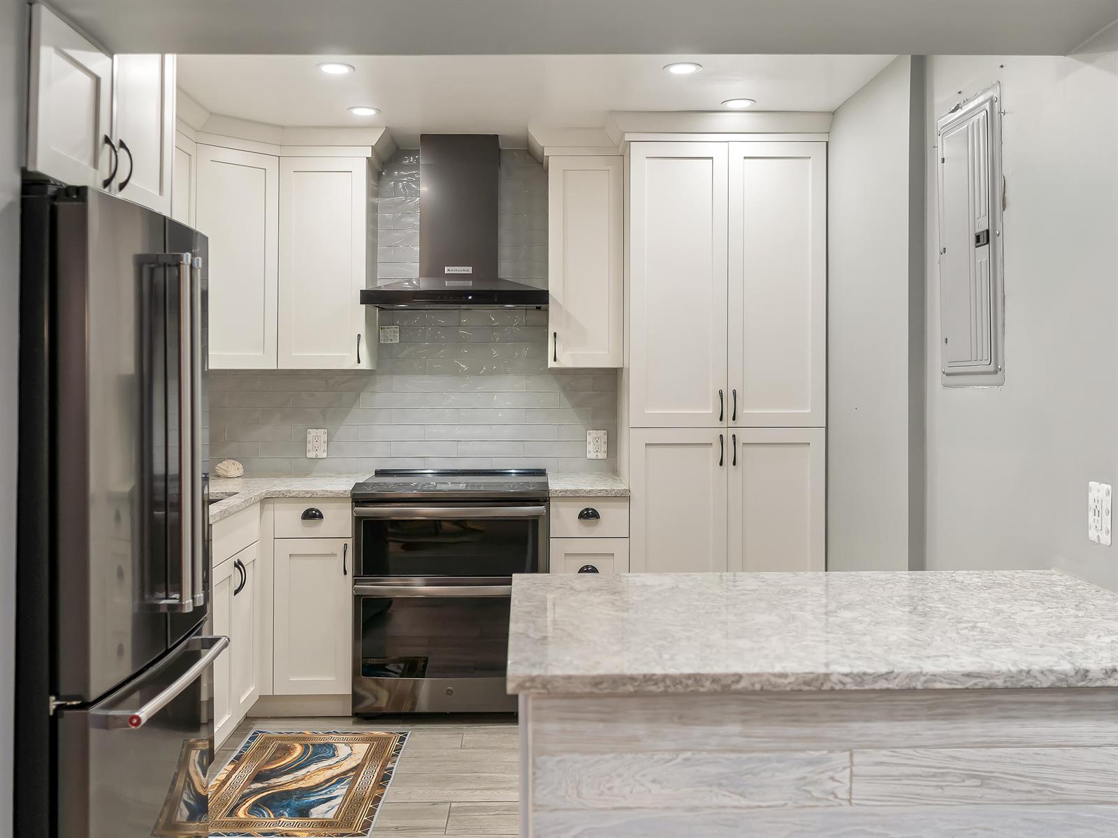A modern kitchen features white cabinets, stainless steel appliances, a tiled backsplash, and stone countertops — 2000 S Ocean Boulevard, Pompano Beach FL 33062, POMPANO BEACH, FL