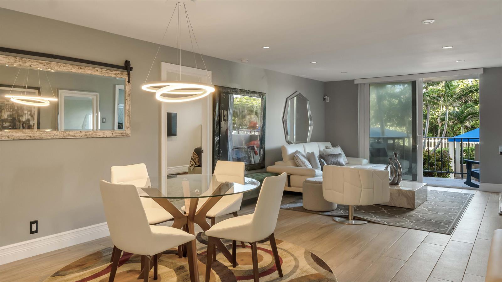 A dining area with a glass table and modern lighting opens into a living room — 2000 S Ocean Boulevard, Pompano Beach FL 33062, POMPANO BEACH, FL