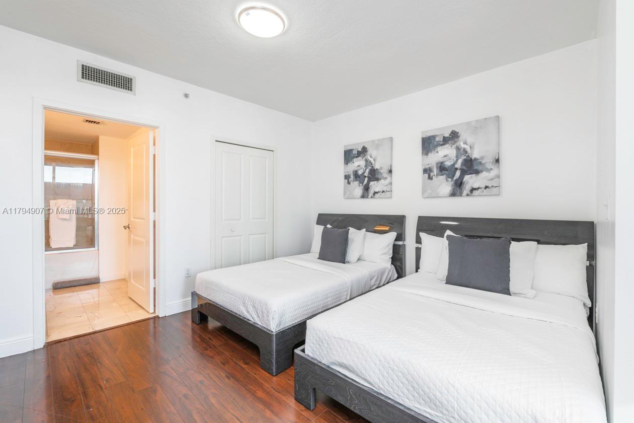 A bedroom features two beds with dark wood frames, white bedding, and an attached bathroom — 170 SE 14th St # 1905, Miami FL 33131, MIAMI, FL