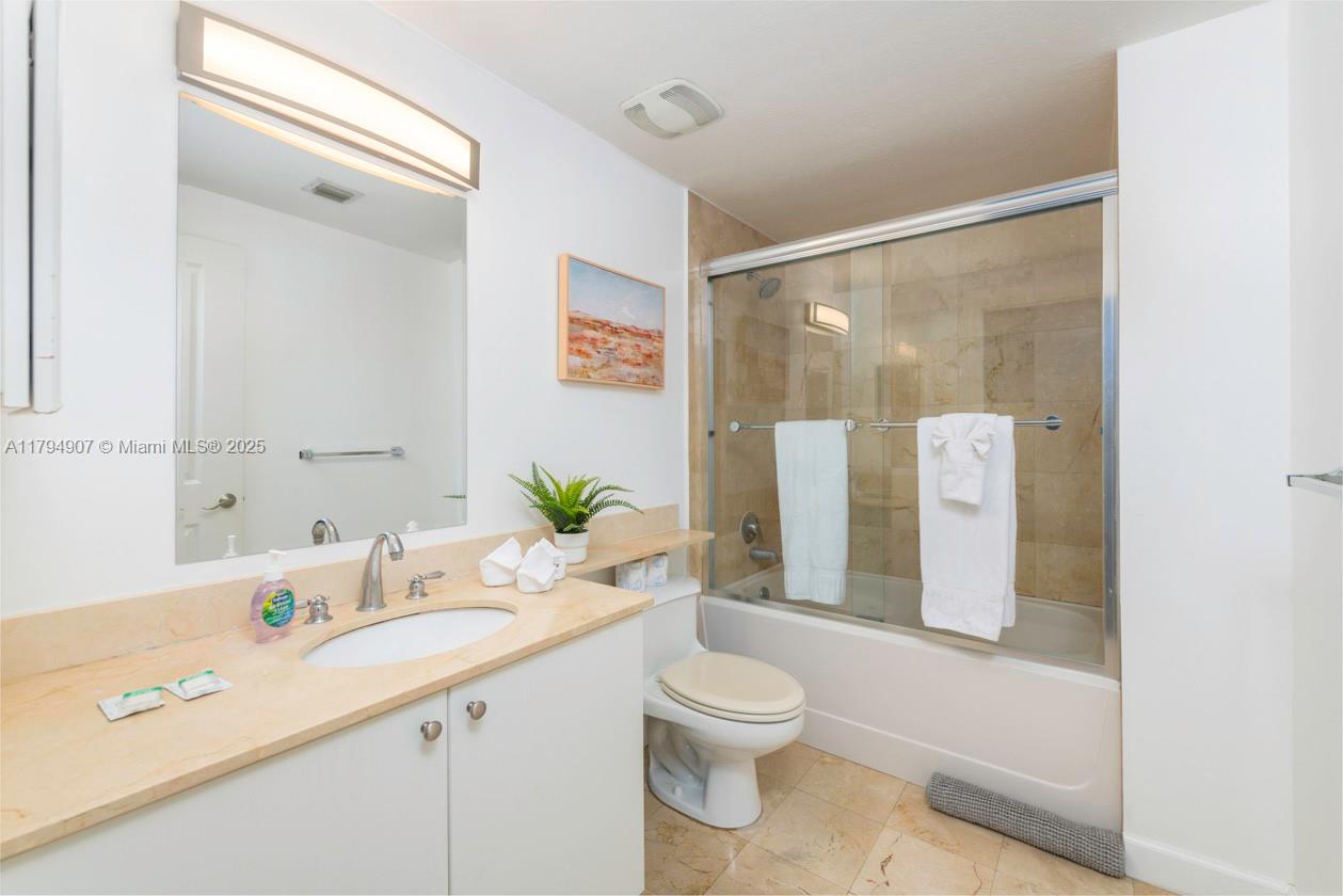 A bathroom features a vanity with a beige countertop, a toilet, and a glass-enclosed tub — 170 SE 14th St # 1905, Miami FL 33131, MIAMI, FL