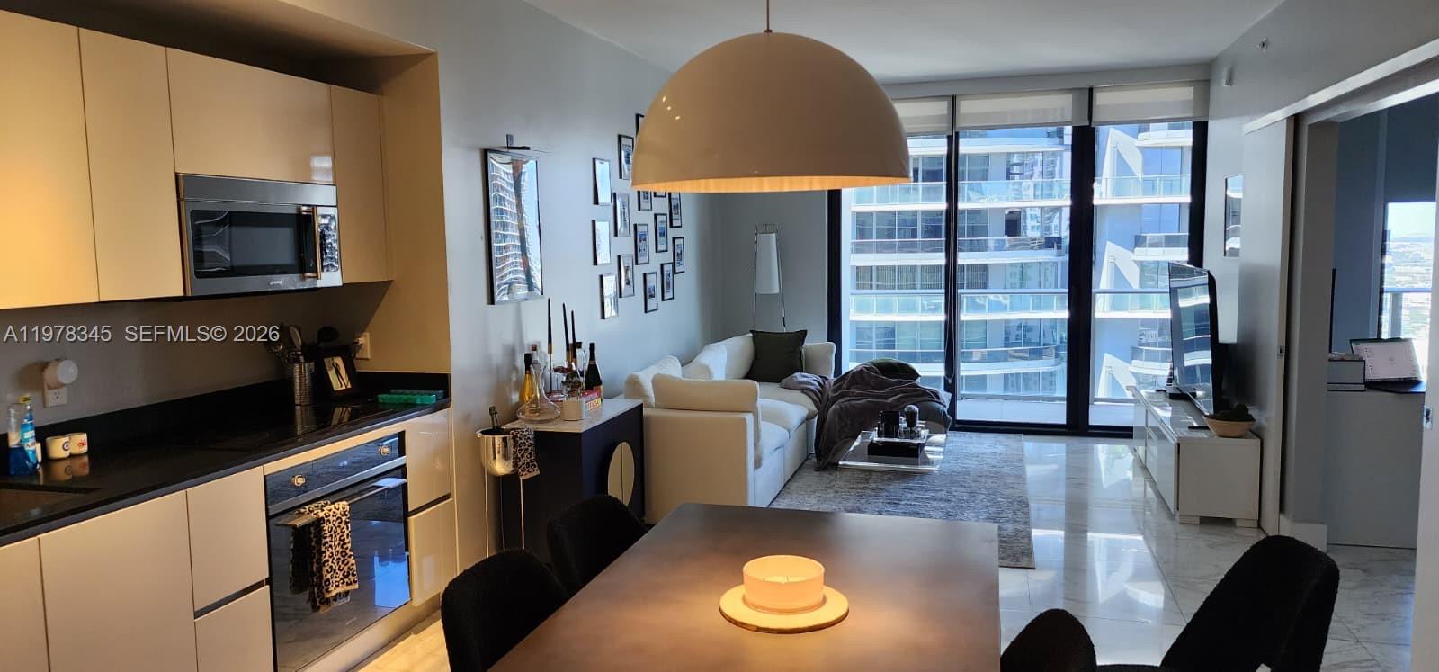 An open-concept kitchen and living area features modern cabinetry, a dining table, and floor-to-ceiling windows — 1010 Brickell Ave # 4208, Miami FL 33131, MIAMI, FL