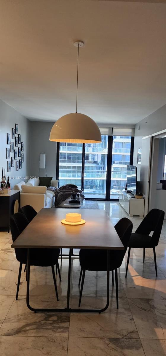 A dining area with a modern table and chairs sits before a living room with floor-to-ceiling windows — 1010 Brickell Ave # 4208, Miami FL 33131, MIAMI, FL