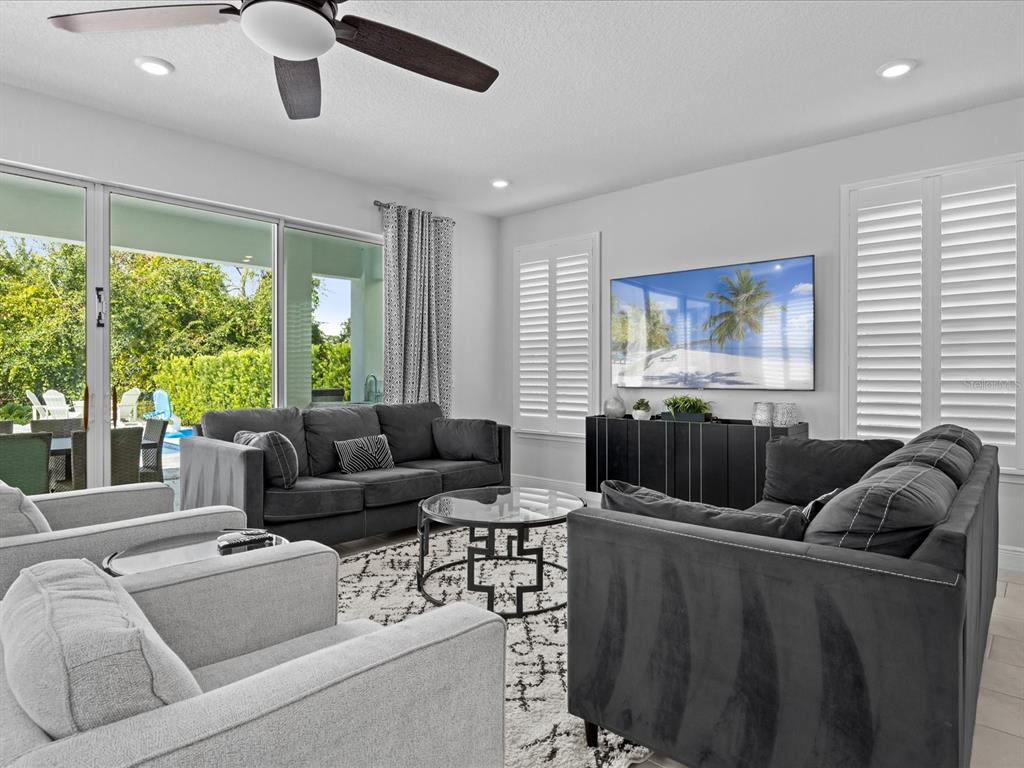 A living room features dark gray sofas, a glass coffee table, and a wall-mounted television — 832 DESERT MOUNTAIN COURT, REUNION, FL