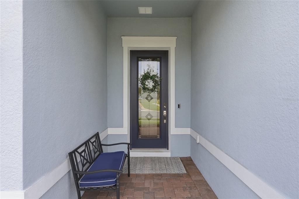 A covered entryway features a dark blue front door with a glass insert and bench — 15031 CANOPY COVER DRIVE, WINTER GARDEN, FL