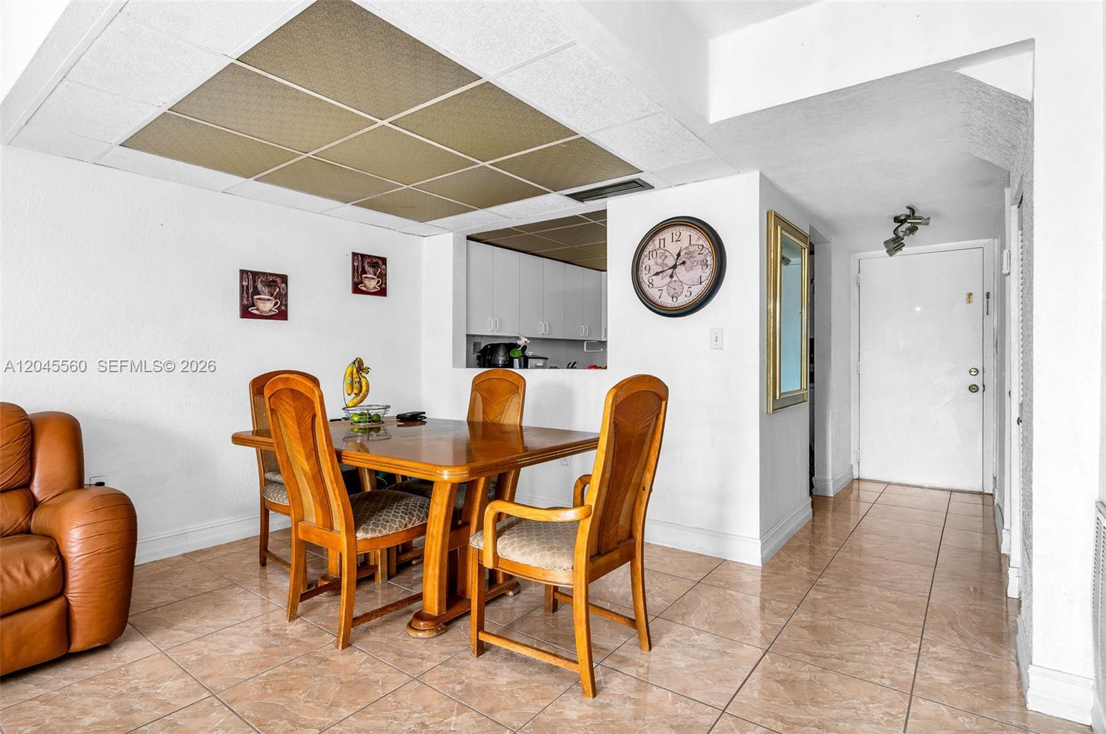 A dining area features a wooden table, four chairs, tile flooring, and a drop ceiling — 6600 W 2nd Ct # 24, Hialeah FL 33012, HIALEAH, FL