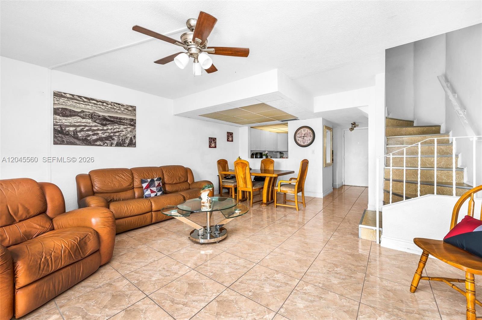A living and dining area features tan tile floors, leather furniture, and a staircase — 6600 W 2nd Ct # 24, Hialeah FL 33012, HIALEAH, FL