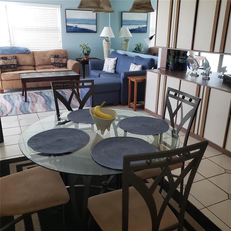 A dining area with a glass table and chairs sits in front of a living room — 1571 S ATLANTIC AVENUE UNIT 203, NEW SMYRNA BEACH, FL