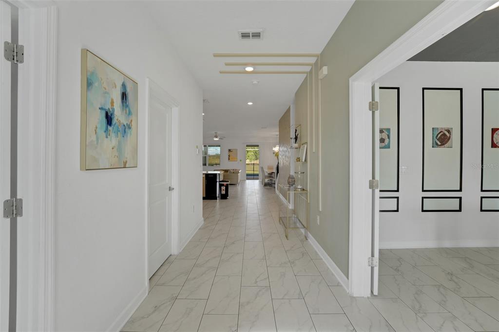 A bright hallway with marble-look tile flooring leads toward an open-concept kitchen and living area — 9262 SOMMERSET HILLS DRIVE, DAVENPORT, FL