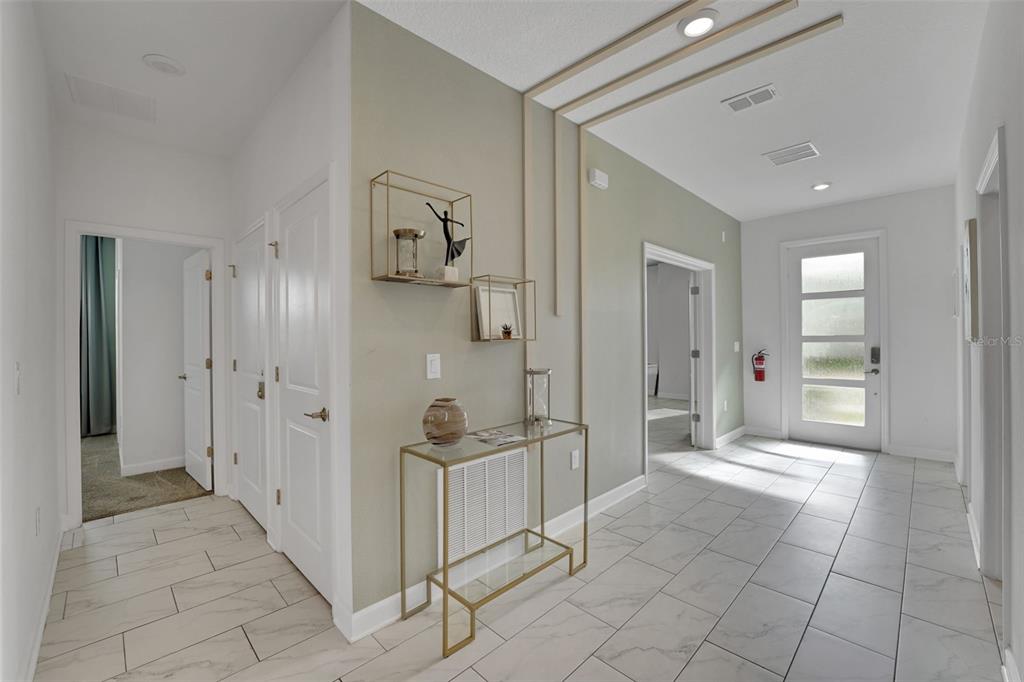 A bright entryway features white tile floors, a gold console table, and decorative wall molding — 9262 SOMMERSET HILLS DRIVE, DAVENPORT, FL