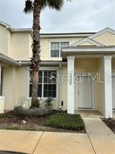 A two-story townhouse exterior features a palm tree, a front door, and a large window — 1705 RETREAT CIRCLE, CLERMONT, FL
