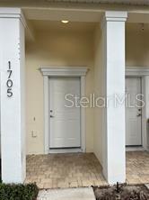 A front entryway with two white doors and a paved porch between two columns — 1705 RETREAT CIRCLE, CLERMONT, FL
