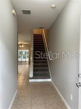 A tiled entryway leads to a carpeted staircase in a home with light gray walls — 1705 RETREAT CIRCLE, CLERMONT, FL