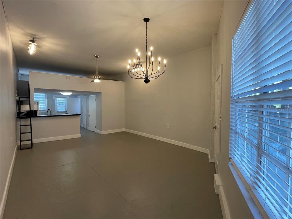 An open-concept living area features a chandelier, gray flooring, and an adjacent kitchen with counters — 2305 W TEXAS AVENUE UNIT 5, TAMPA, FL