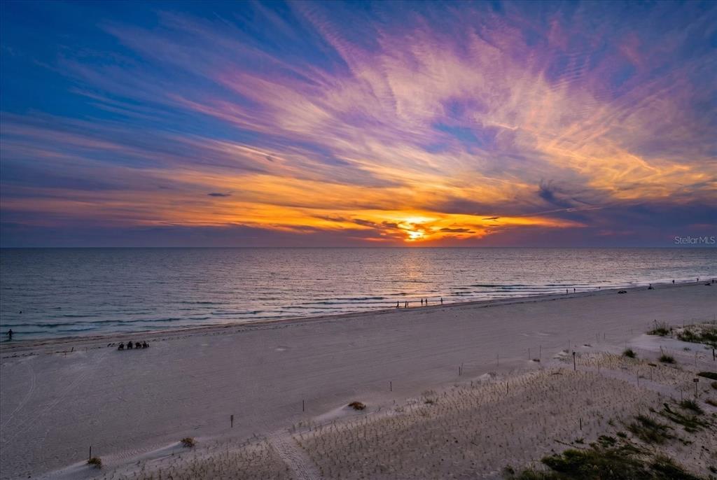 A wide, sandy beach at sunset with a vibrant, colorful sky over the ocean — 19816 GULF BOULEVARD UNIT 501, INDIAN SHORES, FL