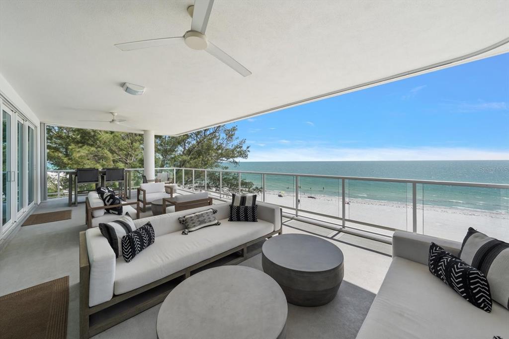 A spacious covered balcony features outdoor seating, concrete tables, and a direct view of the ocean — 19816 GULF BOULEVARD UNIT 501, INDIAN SHORES, FL