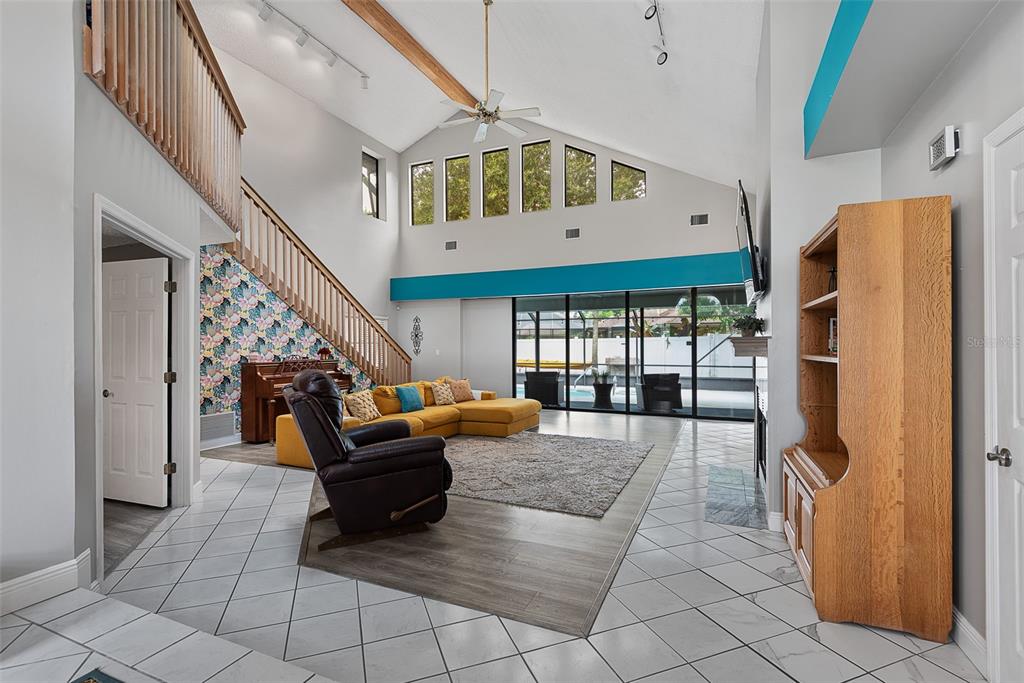 A living room features a vaulted ceiling, a yellow sectional sofa, and a staircase — 3 ECHO WOODS WAY, ORMOND BEACH, FL