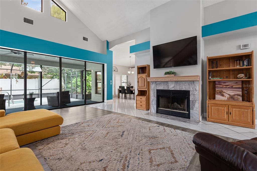 A living room features a stone fireplace, a wall-mounted television, and teal accent walls — 3 ECHO WOODS WAY, ORMOND BEACH, FL
