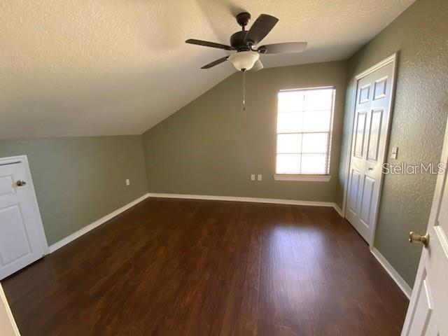 An attic bedroom features dark wood-look flooring, a sloped ceiling, a ceiling fan, and windows — 5005 CITY STREET UNIT 1335, ORLANDO, FL