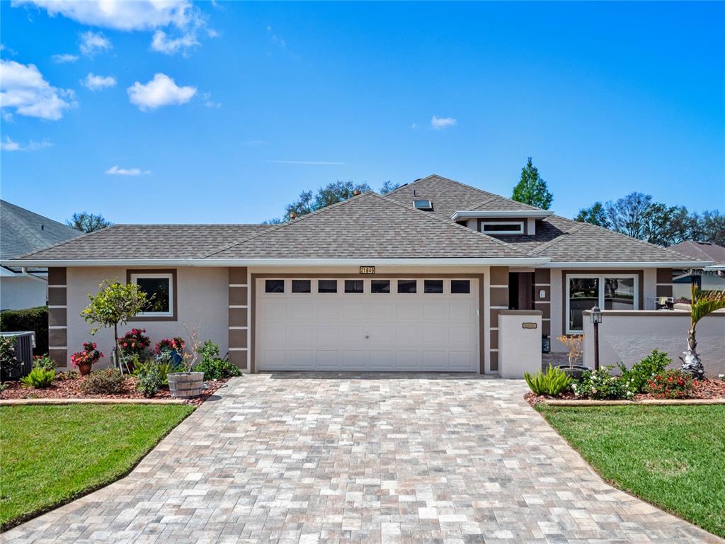 A single-story house with a paved driveway, a two-car garage, and a landscaped front yard — 21849 TARTAN STREET, LEESBURG, FL