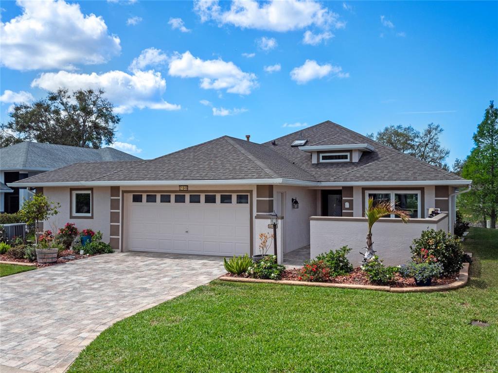 A single-story house with a two-car garage, a paved driveway, and a front courtyard — 21849 TARTAN STREET, LEESBURG, FL