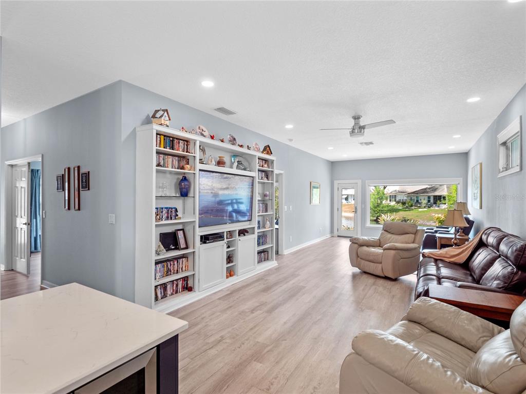 A living room features light wood flooring, a large built-in media center, and leather furniture — 21849 TARTAN STREET, LEESBURG, FL