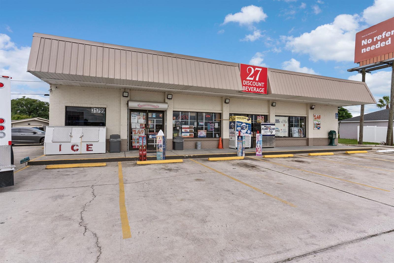 The exterior of a single-story commercial building with a large parking lot in front — 31799 Us Hwy 27, FL 33844, FL