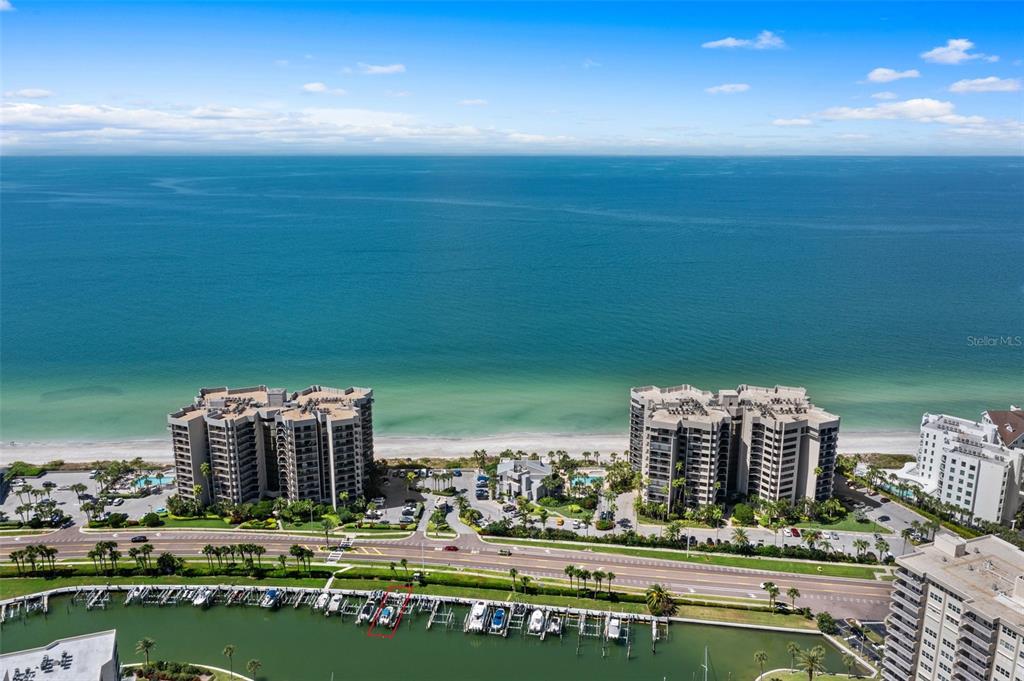 An aerial view shows two beachfront high-rise condominiums overlooking the ocean and a boat slip — 1660 GULF BOULEVARD UNIT 706, CLEARWATER BEACH, FL