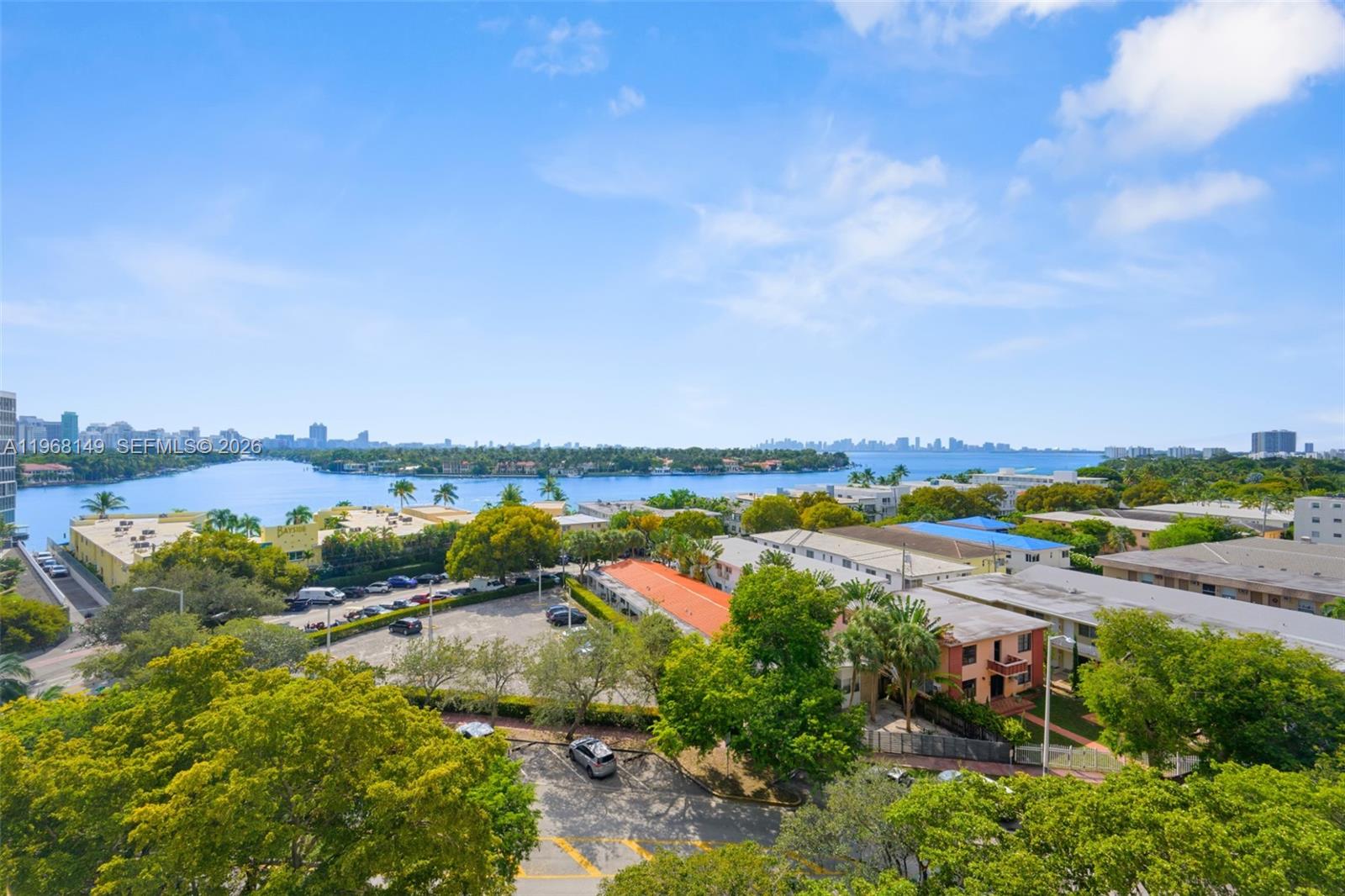 An elevated view shows a parking lot, surrounding apartment buildings, and a bay with city skylines — 6900 Bay Dr # 8A, Miami Beach FL 33141, MIAMI BEACH, FL