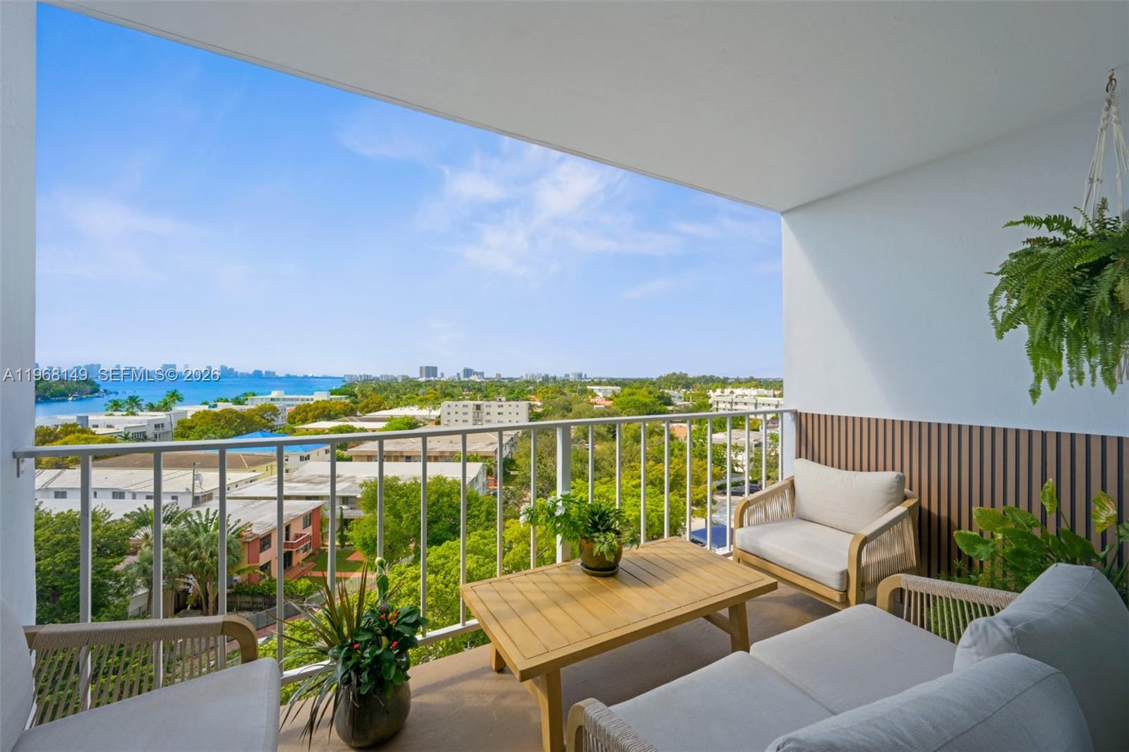 A balcony with outdoor furniture overlooks a residential neighborhood and a distant body of water — 6900 Bay Dr # 8A, Miami Beach FL 33141, MIAMI BEACH, FL