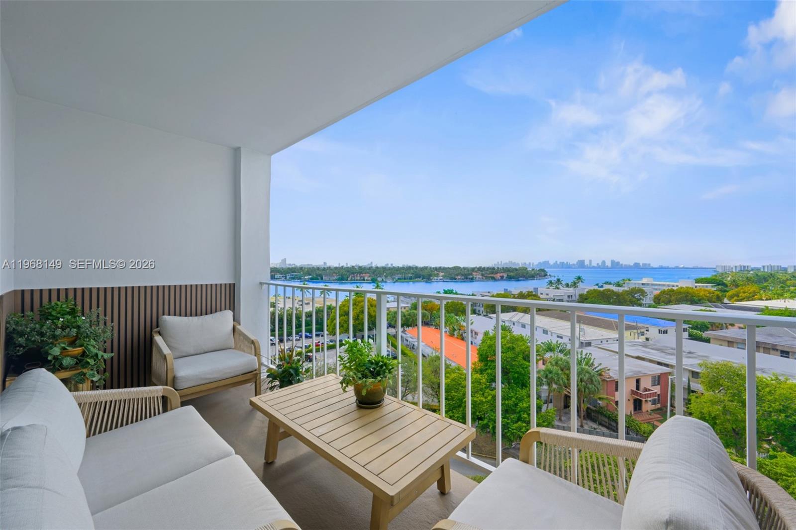 A balcony features outdoor furniture, potted plants, and a panoramic view of the water — 6900 Bay Dr # 8A, Miami Beach FL 33141, MIAMI BEACH, FL