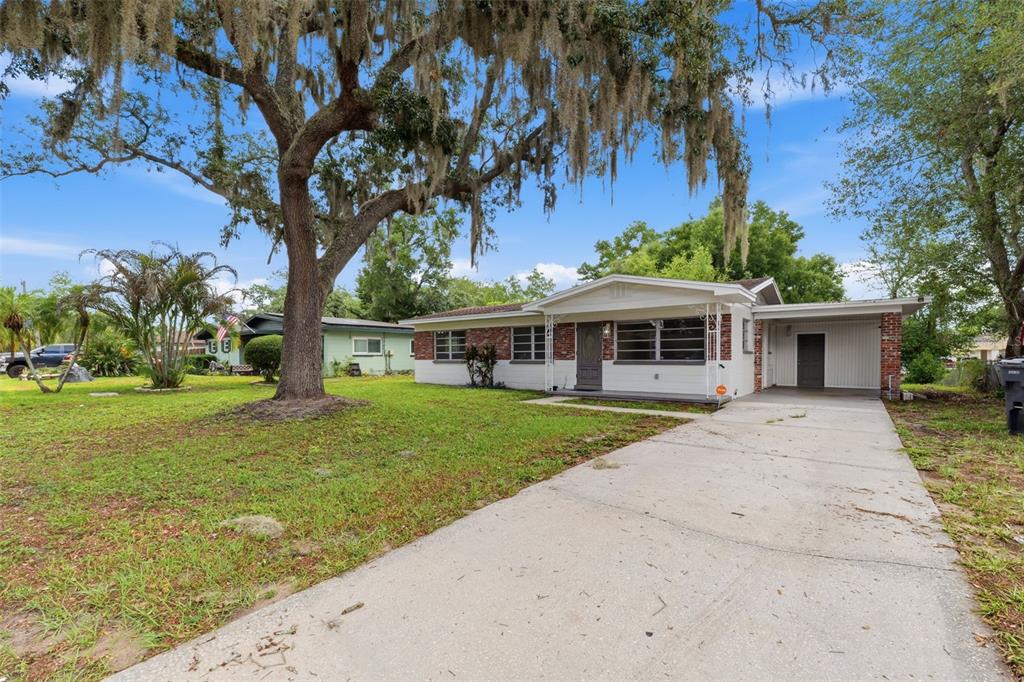 A single-story house with a carport and a large oak tree in the front yard — 7815 PINE HILL DRIVE, TAMPA, FL