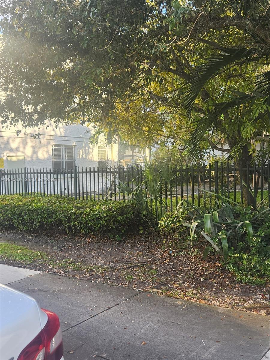 A black metal fence separates a sidewalk from a residential building and trees — 412 NW 4th St, Miami FL 33130, MIAMI, FL