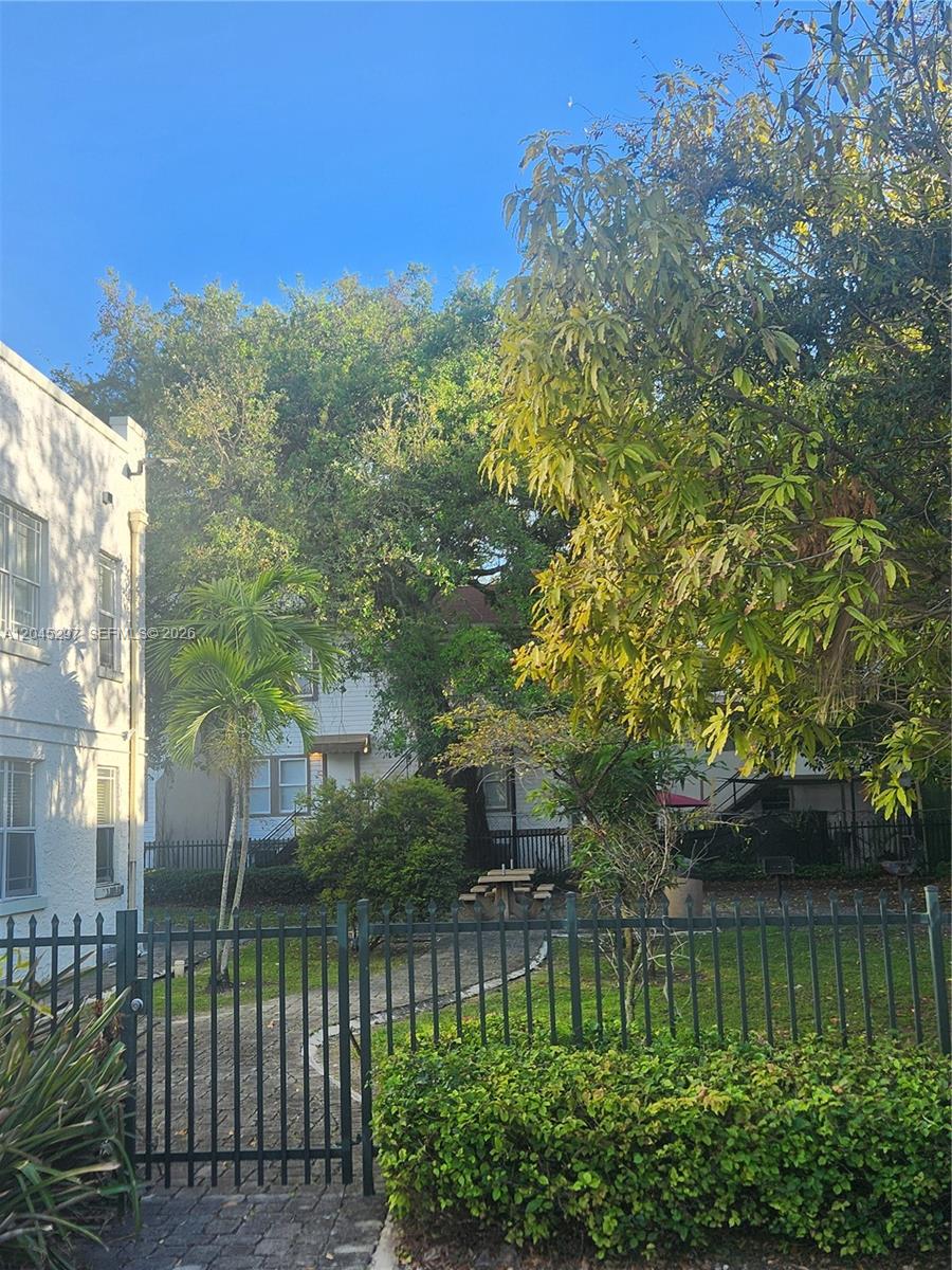 A paved walkway leads through a fenced courtyard with trees, a picnic table, and buildings — 412 NW 4th St, Miami FL 33130, MIAMI, FL
