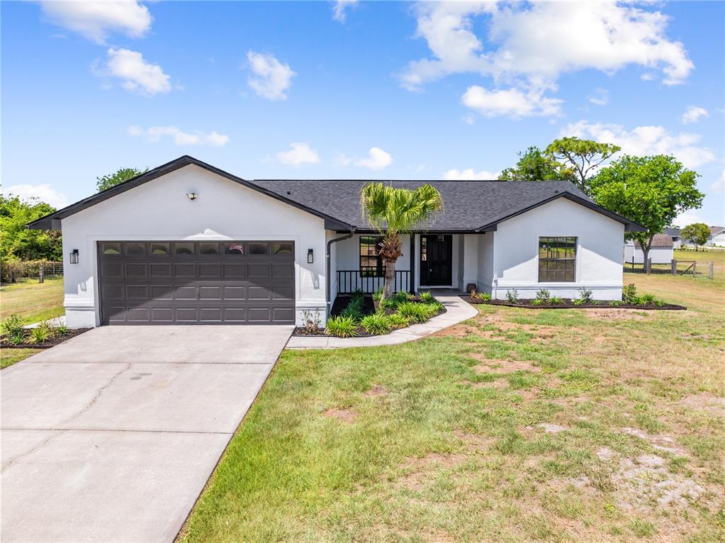 A white, single-story house with a dark roof, garage, and a palm tree in front — 4170 HICKORY TREE ROAD, ST CLOUD, FL