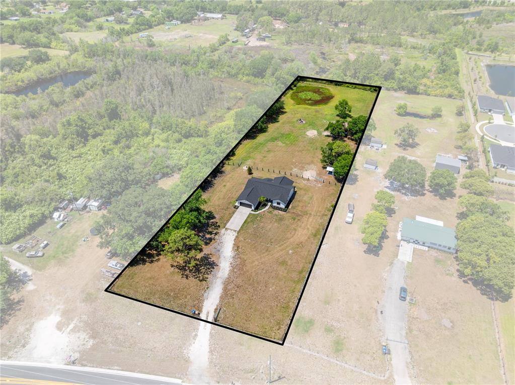 An aerial view shows a house situated on a large, rectangular, fenced-in grassy lot — 4170 HICKORY TREE ROAD, ST CLOUD, FL