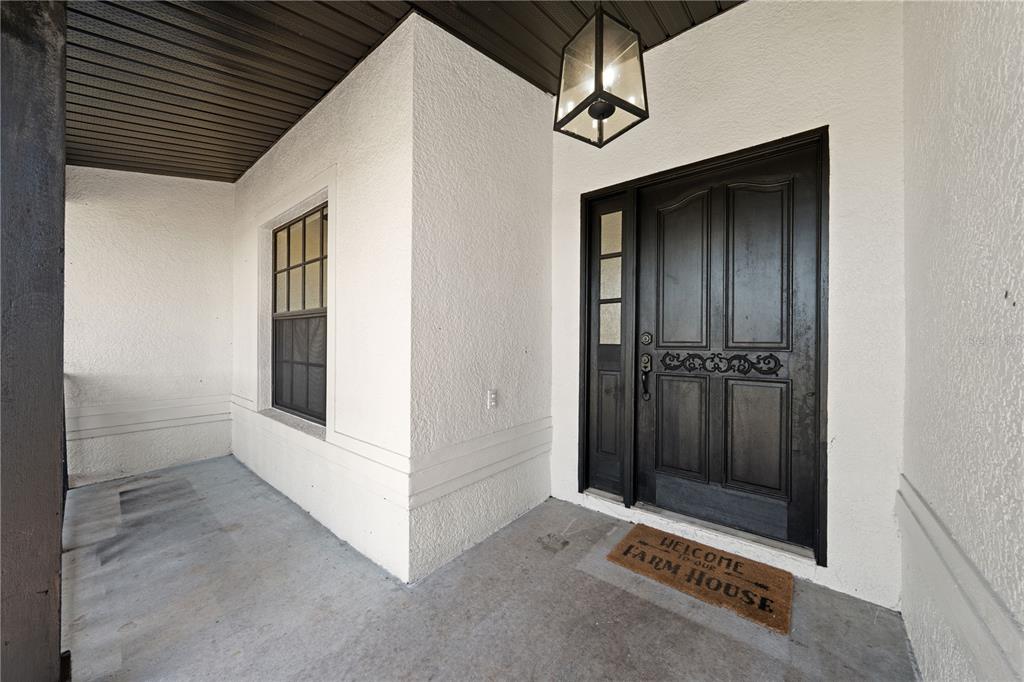A covered entryway features a dark front door, a side window, and a hanging lantern — 4170 HICKORY TREE ROAD, ST CLOUD, FL