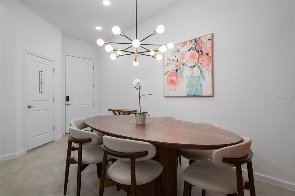 A dining room features an oval wooden table, upholstered chairs, and a modern sputnik chandelier — 10454 EBB TIDE LANE, ORLANDO, FL