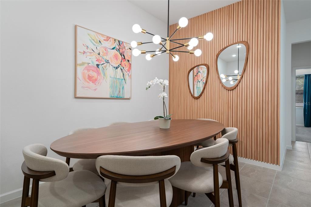 A dining room features an oval wooden table, upholstered chairs, and a slatted wood accent wall — 10454 EBB TIDE LANE, ORLANDO, FL