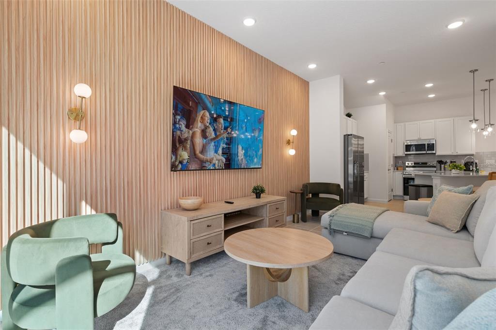 A living room features a slatted wood accent wall, a television, and a light-colored sofa — 10454 EBB TIDE LANE, ORLANDO, FL