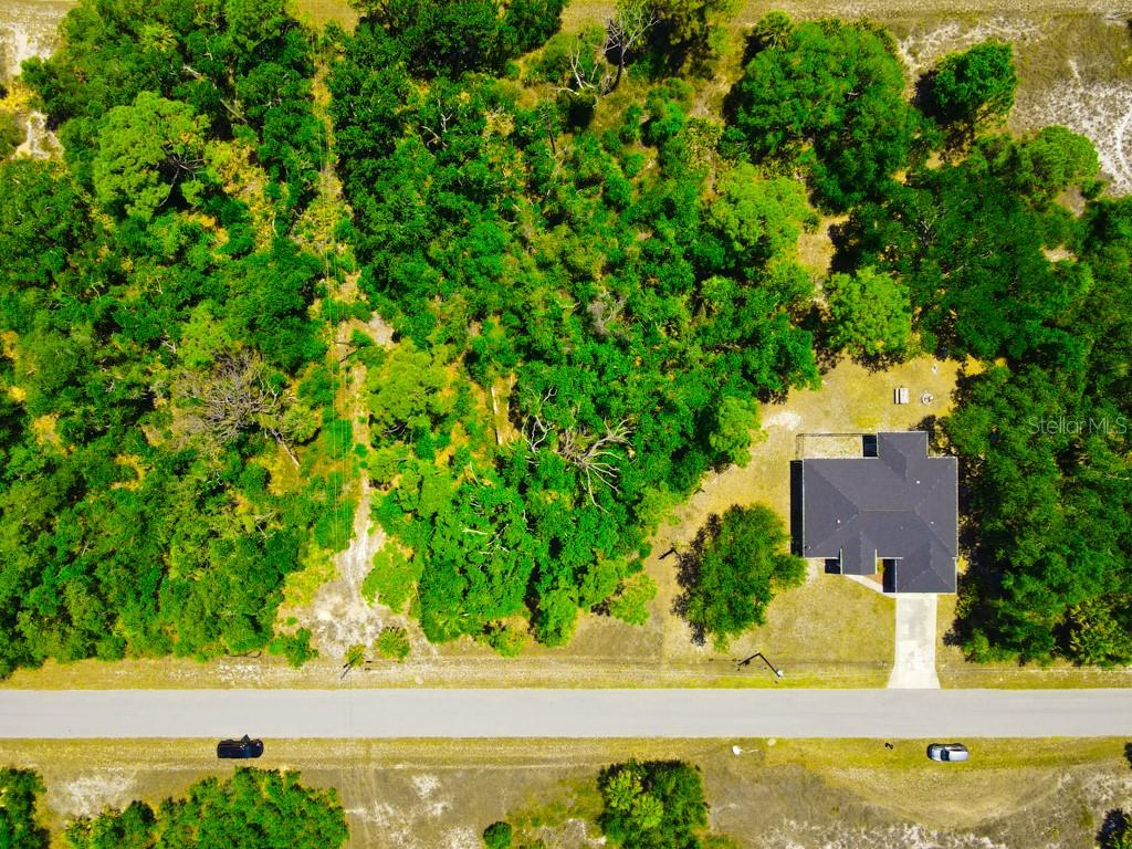 An aerial view shows a house surrounded by dense trees next to a paved road — 15531 FACTORY AVENUE, PORT CHARLOTTE, FL