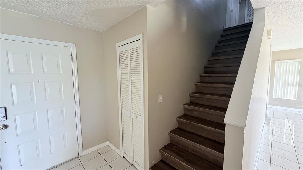 An entryway features a white front door, a louvered closet, and dark wood stairs — 3113 FAIRFIELD DRIVE, KISSIMMEE, FL