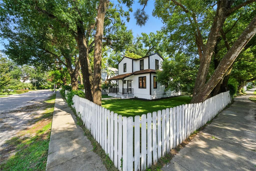 A white two-story house with a picket fence sits on a corner lot with trees — 501 E SPARKMAN AVENUE, TAMPA, FL