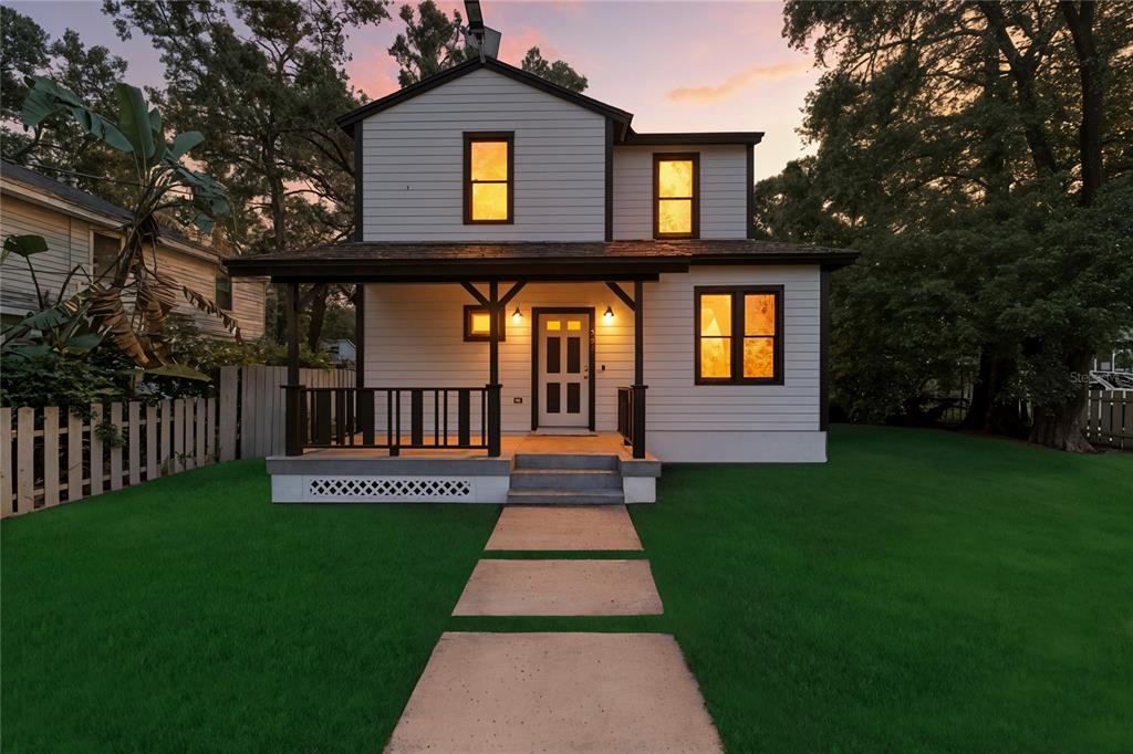 A two-story white house with a front porch and a concrete walkway at dusk — 501 E SPARKMAN AVENUE, TAMPA, FL