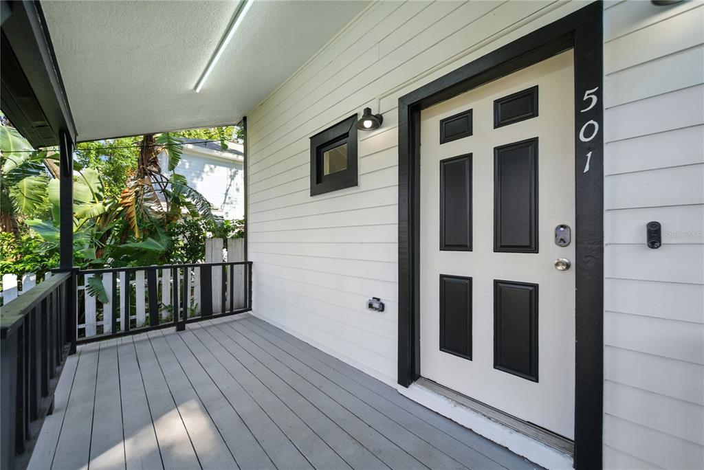 A covered front porch features gray decking, white siding, and a black-trimmed door — 501 E SPARKMAN AVENUE, TAMPA, FL