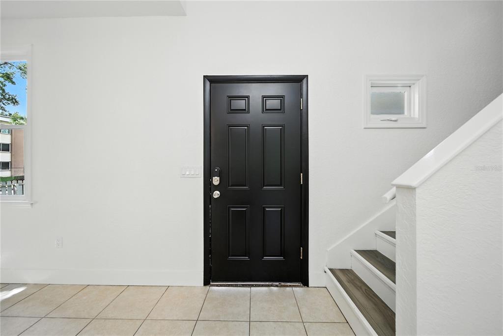 An entryway features a black door, tiled flooring, and a staircase with wood-look treads — 501 E SPARKMAN AVENUE, TAMPA, FL