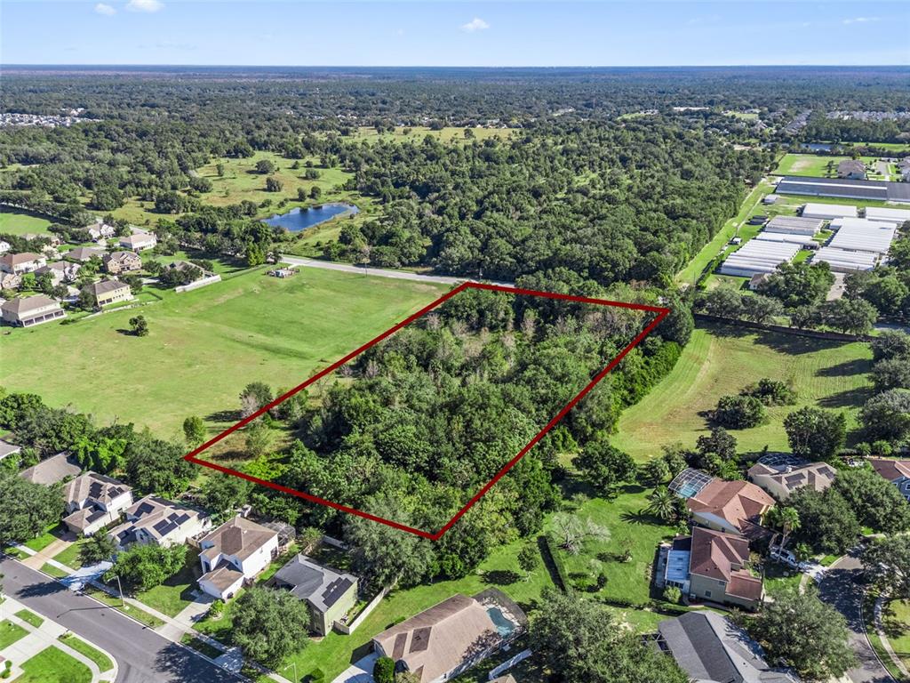 An aerial view shows a rectangular, tree-covered vacant lot outlined in red near residential homes — 2228 VICK ROAD, APOPKA, FL