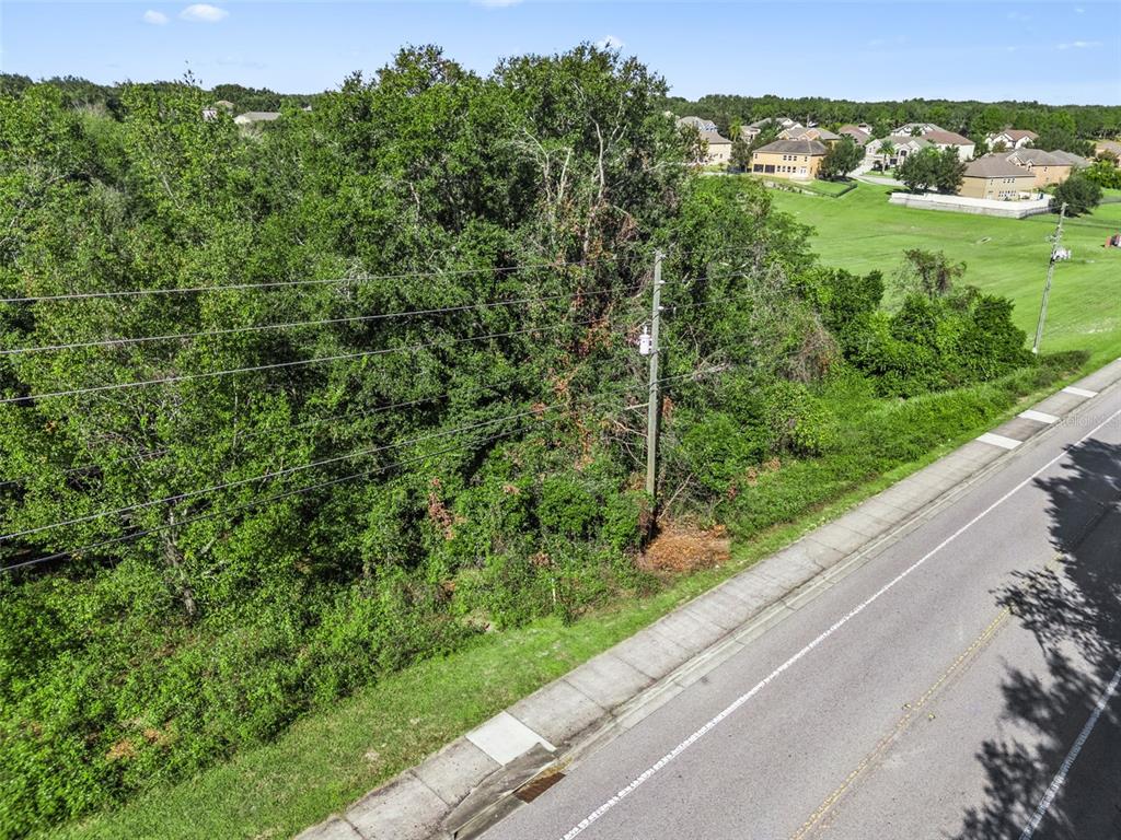 An aerial view shows a wooded lot adjacent to a paved road and suburban homes — 2228 VICK ROAD, APOPKA, FL