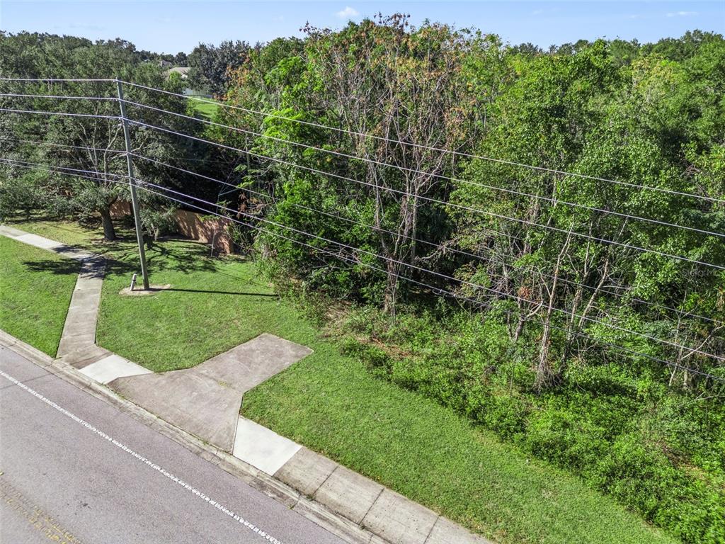 An aerial view shows a vacant residential lot with a concrete driveway and utility lines — 2228 VICK ROAD, APOPKA, FL